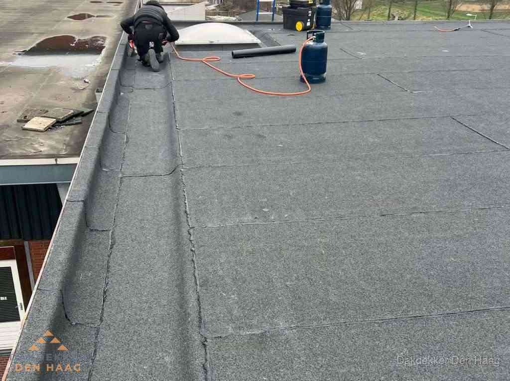 Dakdekker repareert bitumen dakbedekking op groot plat dak in Den Haag Dakdekker repareert bitumen dakbedekking op groot plat dak in Den Haag